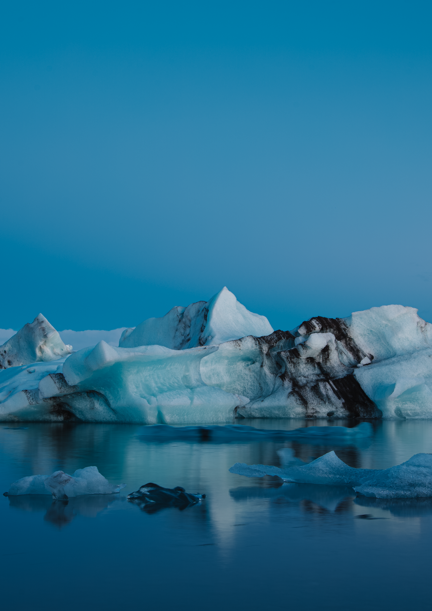 Paisagem de icebergs e blocos de gelo sobre água calma sob céu azul