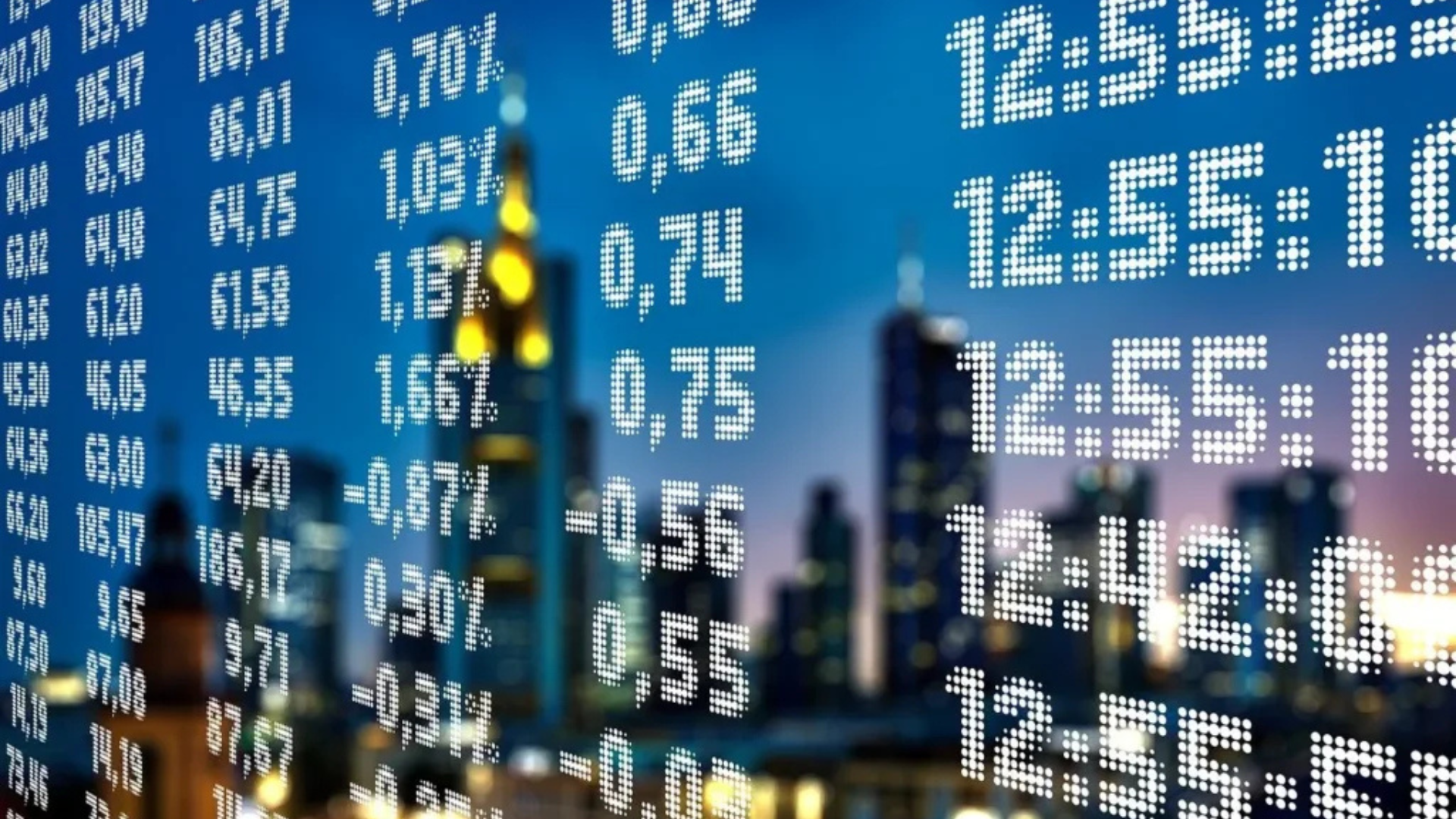Painel digital com cotações financeiras sobre cidade ao fundo ao entardecer
