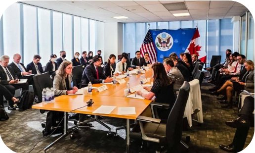 Foto de reunião diplomática com bandeiras dos EUA e do Canadá