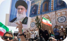 Manifestantes com bandeiras do Irã e retrato do líder supremo iraniano